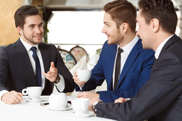 Getting down to business. Handsome men wearing suits discuss business at the restaurant