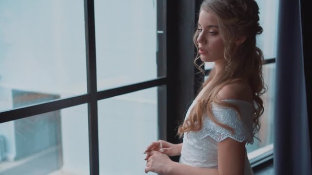sweet lady with blond hair and tnder skin posing for camera in medieval room, long white dress with open soulders, cute curls of blond hair in young girl, maid with tender nude makeup video portrait