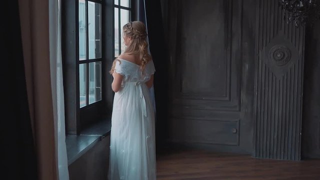 mysterious ghost in old dark castle, girl with blond hair and white long dress with open shoulders standing at large window, the Greek goddess Aphrodite, image of white swan of fate, no face
