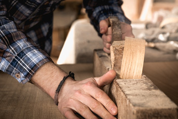 Carpenter working on wood using wood retro old ancient planer. Workshop background