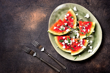 Fresh summer grilled watermelon salad with feta cheese, mint, onions on brown background