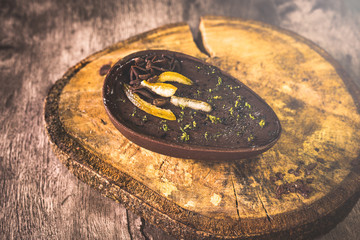 Chocolate egg with filling for Easter on wooden background. Easter egg stuffed with chocolate and coffee.