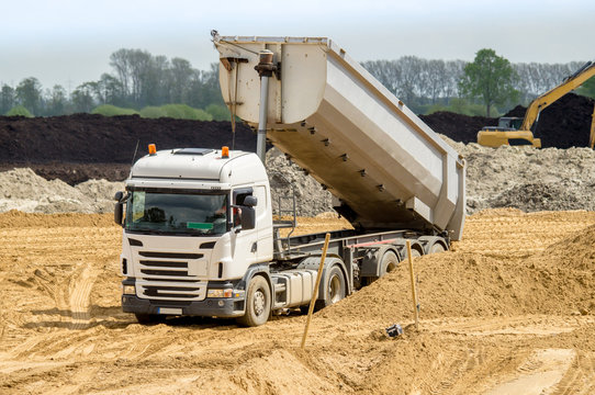 Stra&szlig;enbau - Lastkraftwagen mit Auflieger kippt Sand ab