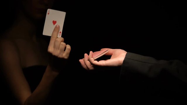 Man holding card deck, woman choosing ace of hearts and showing into camera