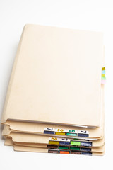 A stack of color-coded and numbered yellow file folders containing sheets of papers, files and documents set on a white background.