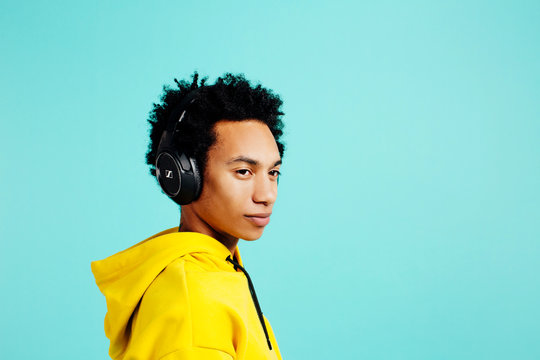 Portrait of a young man with headphones looking to the side,  isolated on blue background