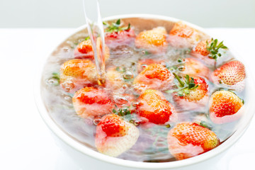 Strawberries soaked in water. Washing fresh fruit on white.