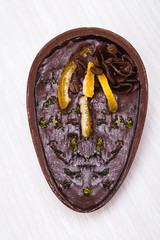 Chocolate egg with filling for Easter on wooden background. Easter egg stuffed with chocolate and coffee.