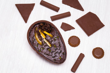 Chocolate egg with filling for Easter on wooden background. Easter egg stuffed with chocolate and coffee.
