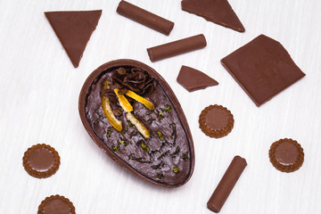 Chocolate egg with filling for Easter on wooden background. Easter egg stuffed with chocolate and coffee.