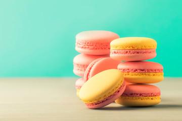 Pink yellow macaroons cakes on gray blue table background, place for text, trendy minimalism style, selective focus