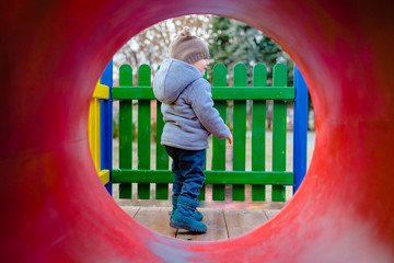 Fototapeta na wymiar Portrait of Little Boy trough the Tunnel Tube Slide at the Playground park