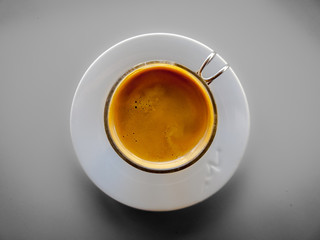 Taza de café solo con plato blanco y taza de cristal en vista cenital.