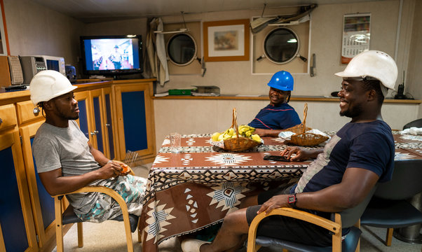 Seamen crew onboard a ship or vessel having fun watching TV. Recreation during at sea