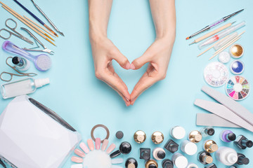 beautifully groomed fingernails in the form of a heart on the desktop with tools for manicure. Care...
