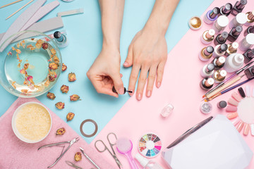 Concept of nail art. Woman gives herself a manicure on a white table