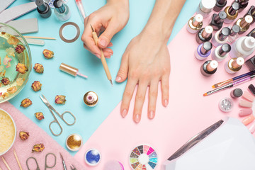 Manicure - means for creating, gel polishes, all for nail care, beauty concept, care. On a blue and pink background, a woman receives a manicure of nails.