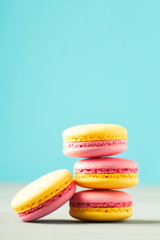 Pink yellow macaroons cakes on gray blue table background, place for text, trendy minimalism style, selective focus