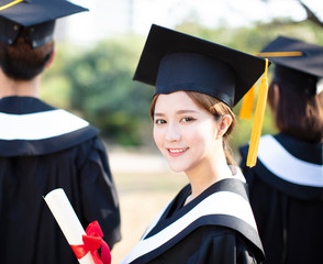 smiling young woman at graduation showing her diploma
