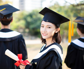 smiling young woman at graduation showing her diploma