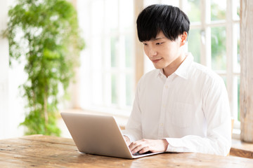 young asian man using laptop in living room