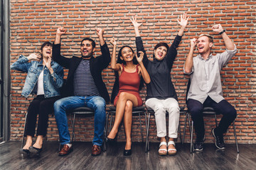 Successful of group of casual business sitting relax celebrating their triumph with arms up on wall background.Teamwork concept