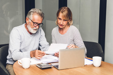 Senior couple reading documents and calculating bills to pay in living room at home.Retirement...