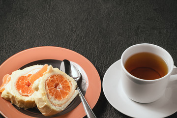 Sweet roll with whipped cream and tangerine filling and a cup of tea