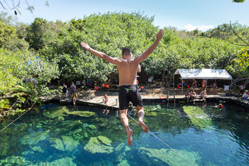 Man jumps off a cliff into the Cristalino cenote in Mexico.