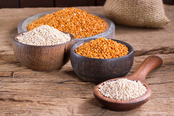 Quinoa seeds and red millet in bowl on rustic wood