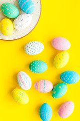 Festive Easter table. Colorful Easter eggs on plate on yellow background top view