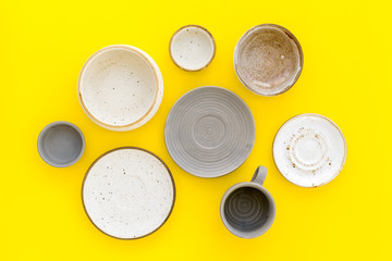 Kitchen concept. Crockery kit. Empty ceramic plates and mugs on yellow background top view
