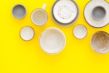 Ceramic tableware pattern. Empty plates and mugs on yellow background top view space for text