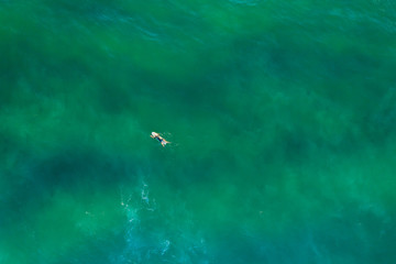 Looking down at surfer in turquoise ocean water at sunrise with copy space