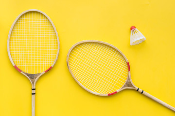 Badminton concept. Badminton rackets and shuttlecock on yellow background top view