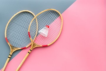 Badminton equipment. Badminton rackets and shuttlecock on pink and grey background top view copy space