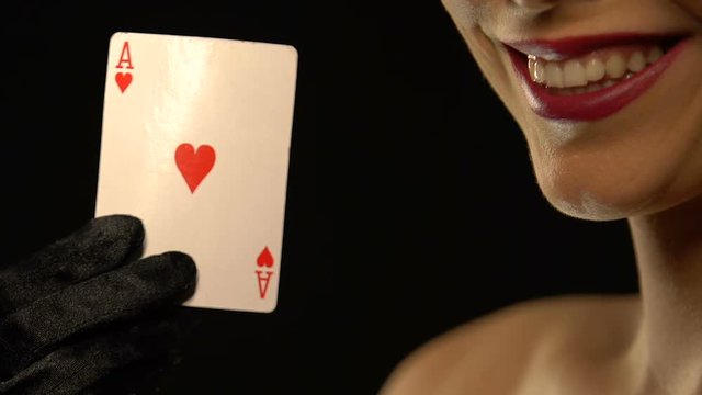 Smiling lady showing ace of hearts into camera, isolated on black background