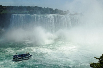 Touristic boat approaching the middle of the Niagara Horseshoe Falls bowl. The falls height is 57 m and they throw down about 6,400 m3 water per second