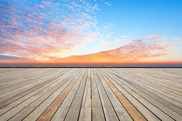 Fototapeta na wymiar Empty wooden platform and modern city skyline with beautiful colorful clouds at sunset