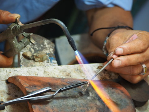 close up of the hand of a dark leather master working with jewelry in the Dominican Republic.