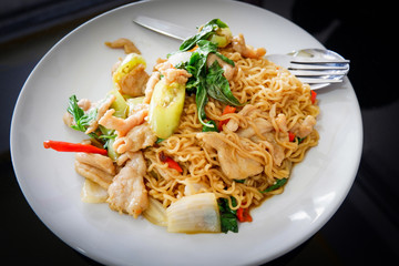 Instant noodle stir fried chicken chili pepper and basil leaf on white plate