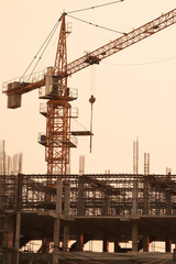 Silhouette building crane and buildings under construction against evening sky.