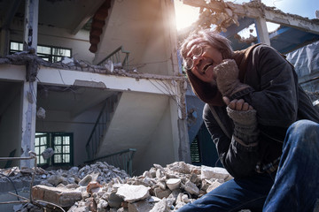 Man in an abandoned building destroyed, crying to lose his house destroyed by disaster or war