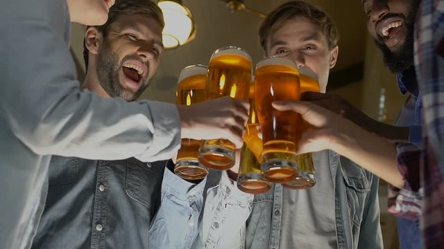 Happy group of friends clinking beer glasses, birthday party celebration in pub
