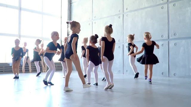 Girl dancer in ballet school learns to dance. Little Ballerina in training in black dancing suit. Children's ballet school.