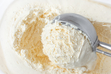 Scooped Vanilla ice cream with a scoop in frozen  container. White ice-cream,  top view.