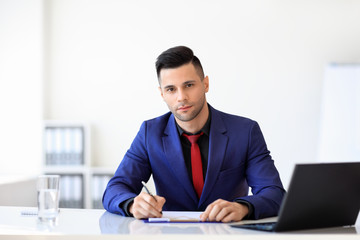 Fototapeta na wymiar Young confident businessman signing document in the office