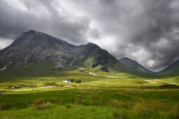 Sunlight on white cottage on River Coupall valley with Stob Dhearg peak of Buachaille Etive Mor range at Glen Coe Scottish Highlands Scotland