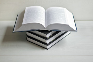 Books and an open book on a light wooden background.