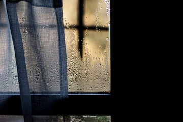 Water drops and curtains taking visibility on a window glass from indoor view